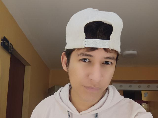DantezSword with white backward cap, brown hair, and brown eyes, wearing a white hoodie, has a neutral expression, and is centered in the image.