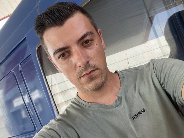 MaxenRace has short, dark hair, brown eyes, and a light green shirt with "XPRAYM7" on it. He's looking at the camera with a slight, serious expression.