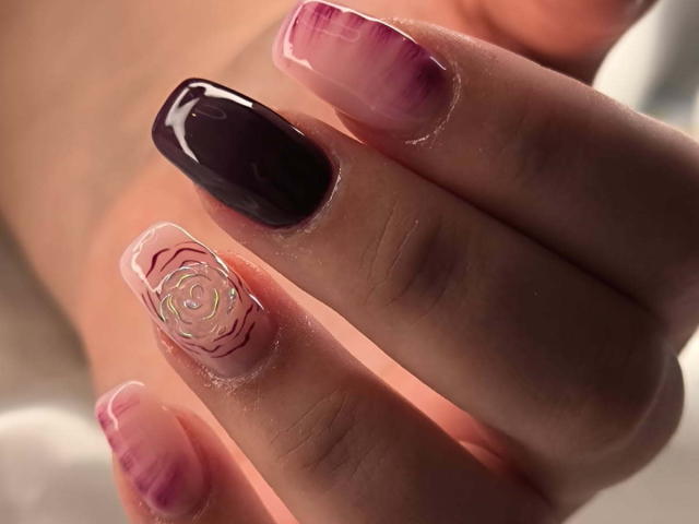 ElvinnaLaFrancaise's nails are glossy and sexy, featuring a dark purple polish on the index, pink with purple tips on the other nails, and a pink floral design on the ring.