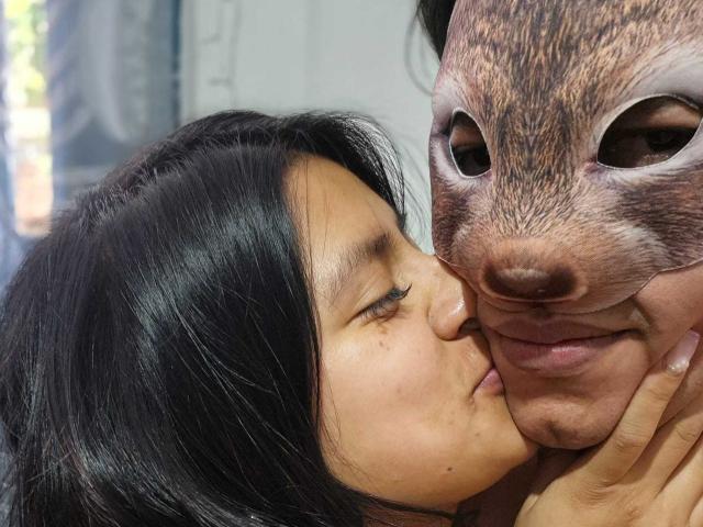 Il viso di Thanem è premuto contro una maschera realistica a forma di scoiattolo, la sua lingua è leggermente fuori, a contatto con il naso della maschera. Ha i capelli neri e indossa l'eyeliner..