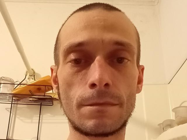 Cumguys69's bald head with a receding hairline, slightly stubbled face, and neutral expression, showing a slight smile. His nose is centered, and his eyes are focused.