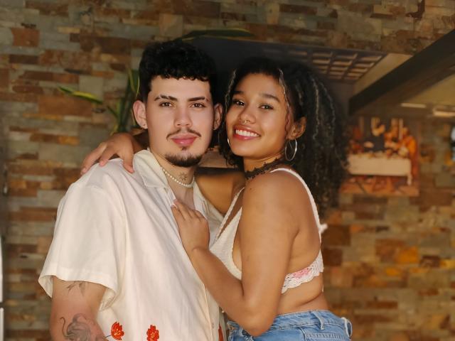 Ashley et Jack, avec des cheveux noirs bouclés et une peau brune, portent un soutien-gorge blanc et embrassent Jack, qui a des cheveux noirs bouclés et une peau claire, et porte une chemise blanche, en souriant. La main de Jack est sur les fesses d'Ashley..