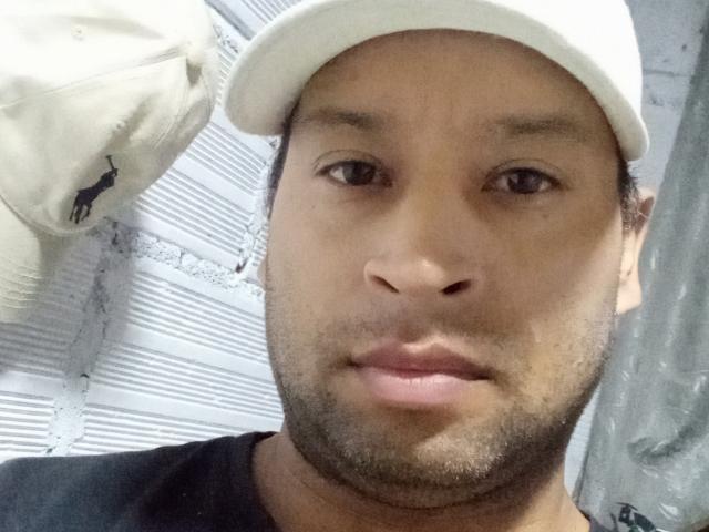 LoganModel has a medium brown skin tone, a short beard, and is wearing a white baseball cap with a black bird logo. He's looking straight at the camera.