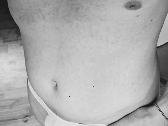 TOMSTERN-hot's onbedekte, lichtelijk gevlekte buik met een kleine navel, draagt witte onderbroek en toont een kleine moel in de buurt van de navel. Monochroom beeld..