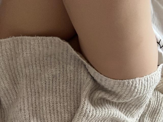 AngelEmma69's butt in a white, ribbed knit sweater, partially covering her bare skin. Her thigh is visible, highlighting the soft texture of the fabric.