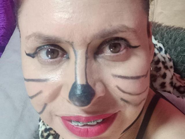 SherahaJade a dessiné des moustaches et un nez de chat sur son visage, avec du crayon noir pour les yeux et du rouge à lèvres, et elle montre ses dents dans un autoportrait. Ses yeux marrons sont fixés sur l'appareil photo..