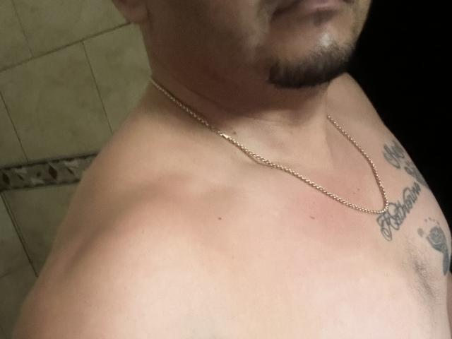 Benjacabo's shirtless upper body with a gold chain, slight beard, and tattoo on the right side of his chest. His skin has a red, irritated patch on his shoulder.