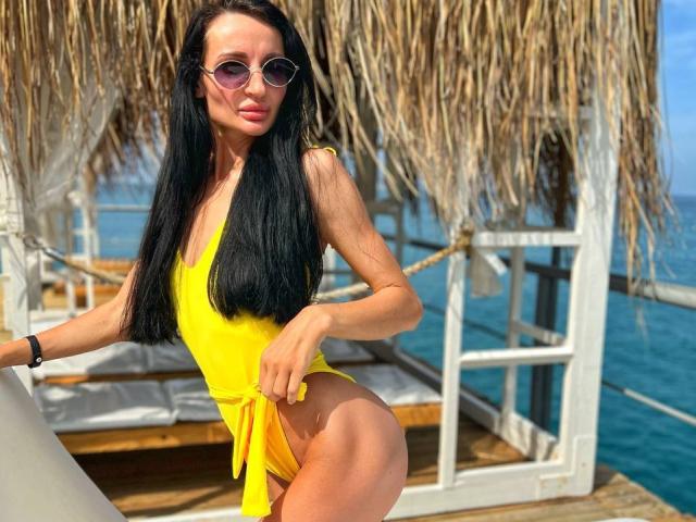 TinaMart with long black hair, wearing a yellow one-piece, showing a big ass and small tits, in sunglasses, on a wooden boat with a thatched roof.