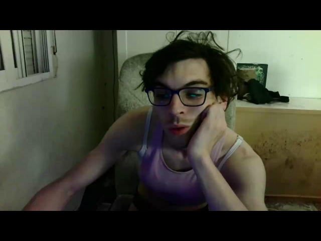 EnzoFx69 with messy brown hair, wearing glasses and a pink sports bra, touching their cheek with one hand, looking slightly annoyed or tired.