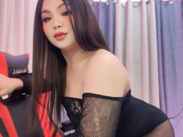 xChabelitaForYou-hot with long brown hair, red lips, black fishnet top, bare shoulders, leaning forward, black chair with red and black stripes, soft light, slightly seductive look.