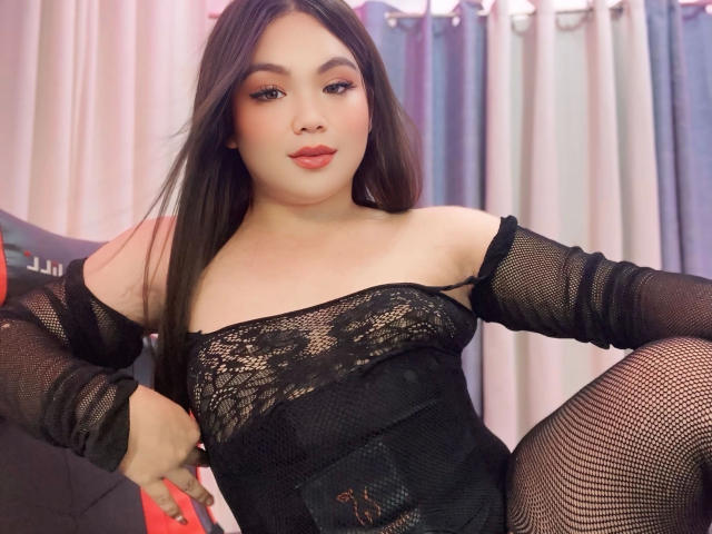 xChabelitaForYou-hot in black lace and fishnet dress, exposing her tits and pussy through sheer fabric, sitting with legs apart, long black hair, pink lipstick, confident expression.
