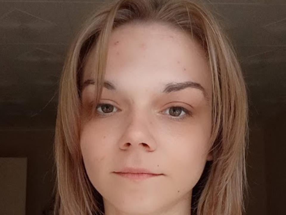 RosyRosa has light brown hair, green eyes, and a slight smile with a small pimple on her forehead. She's looking directly at the camera, with a relaxed expression.