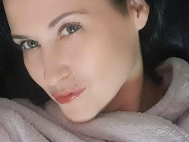 MarryCordy's face, with a slight smile, has glossy pink lips, blue eyes, and a small mole on her right cheek. She's wearing a pink, fuzzy, robe-like garment.