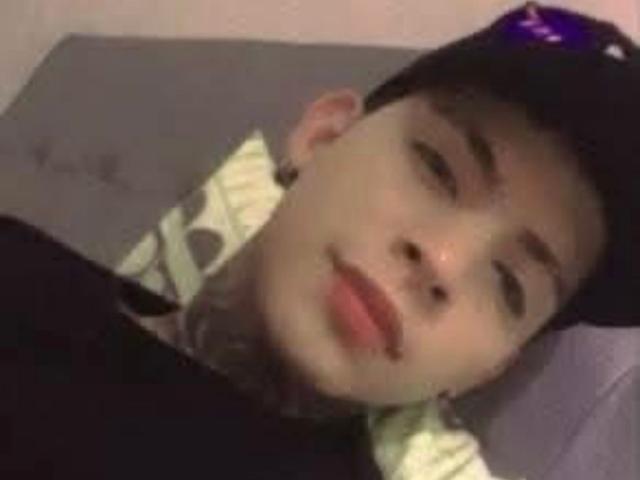 LiamBennett is lying down with a black cap on, pale skin, and tattoos on his neck. He's looking slightly off-camera with a relaxed expression.