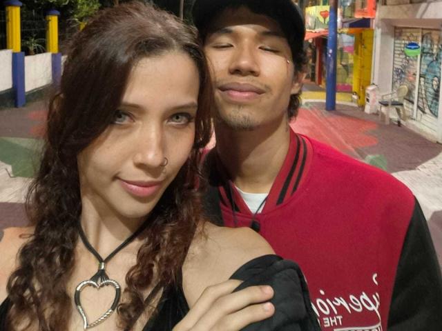 RoxanAndNoah, una ragazza con i capelli ricci castani e una collana a forma di cuore, è in piedi accanto a Noah, un ragazzo con i baffi, che indossa una giacca sportiva rossa e nera..