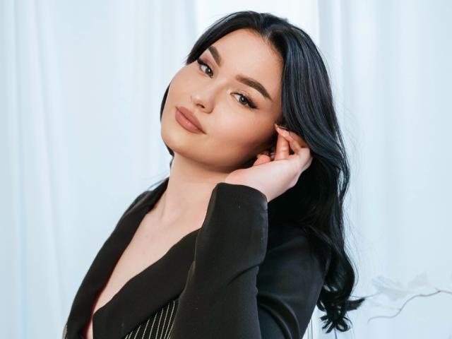 HopeForLove with black hair, wearing a black top, hand on ear, slight smile, soft makeup, light skin, looking at camera, medium tits, sexy, confident, photo.