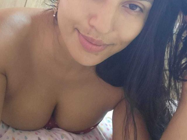 TamaraOriz has medium brown skin, long dark hair, and is smiling with her nose pierced. She's topless with large, visible tits in a red bra.