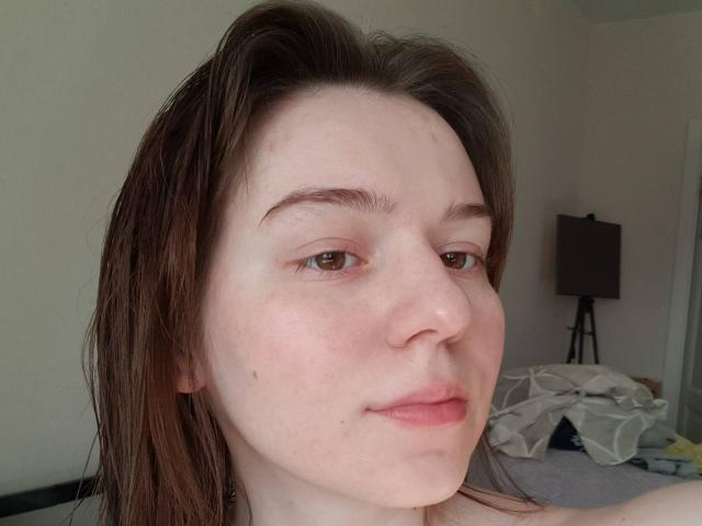 AliceNour's face, showing pale skin, brown eyes, and wet brown hair, with a slight smirk, and her nose is slightly upturned. Her ass isn't visible.