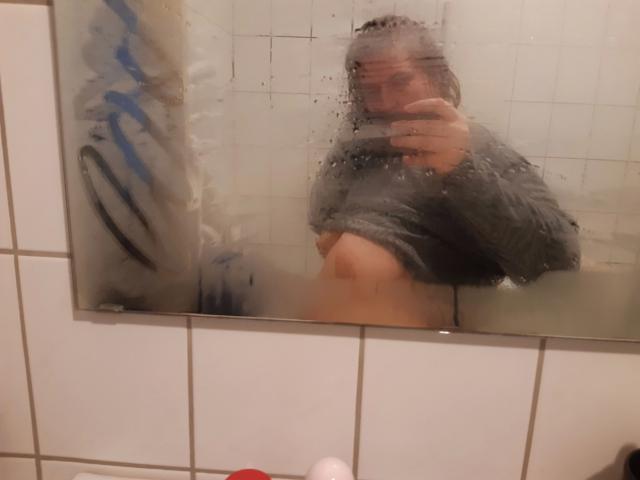 HairyValeri's back is to the camera, wearing a white thong, showing her bare ass, with long dark hair and a small tattoo on her lower back.