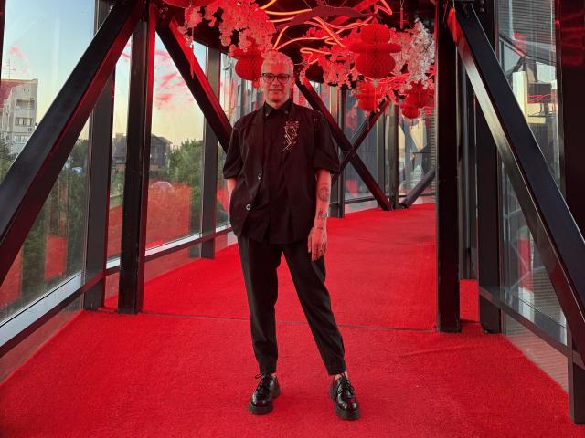 Stylized digital art of a bold red and black flag with a white emblem in the top left. Clean lines, minimal color, geometric design. LuxMiamoto not present. Modern, minimalistic.