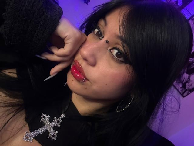 RubyViolete with black pigtails, wearing a white and red nurse hat, black glasses, and a white shirt with red trim, showing her blue eyes and pouty lips.