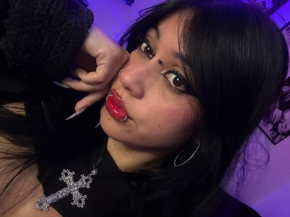 RubyViolete with black pigtails, wearing a white and red nurse hat, black glasses, and a white shirt with red trim, showing her blue eyes and pouty lips.