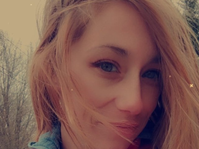 Ryyde's face with blonde hair, blue eyes, and a slight smile, showing a cute nose and full lips, with subtle star effects on a slightly blurry photo.