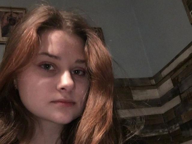 BellaMuse-hot has light brown, slightly wavy hair, a fair skin tone, and a neutral expression. Her brown eyes are slightly open, and she has a small nose ring.