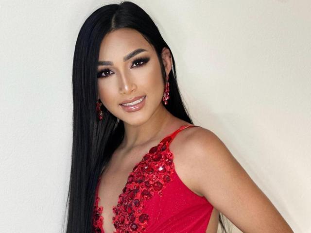 EvelinVillalobos with long black hair, red sequined dress, and red earrings, smiling at the camera. Her tits are small and her pussy is not visible.