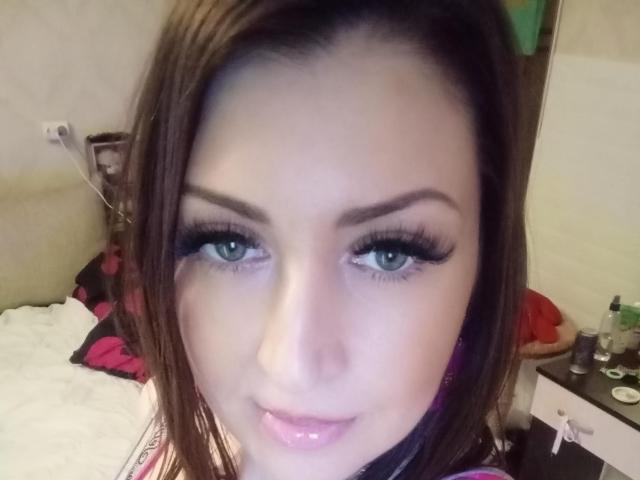 WikiStar with brown hair, green eyes, and glossy pink lips, showing off her long, thick, black eyelashes and slightly parted, shiny pink lips. Her ass is not visible.