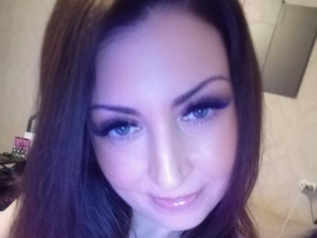 WikiStar has blue eyes, dark brown hair, and is smiling with a glossy pink lip. She's wearing heavy black eyeliner and has a slight blush on her face.
