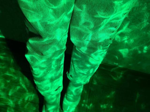 Siyana's green-tinged pants with rippling, water-like textures and subtle shadows, highlighting the fabric's creases and folds. The image focuses on her lower legs and thighs.