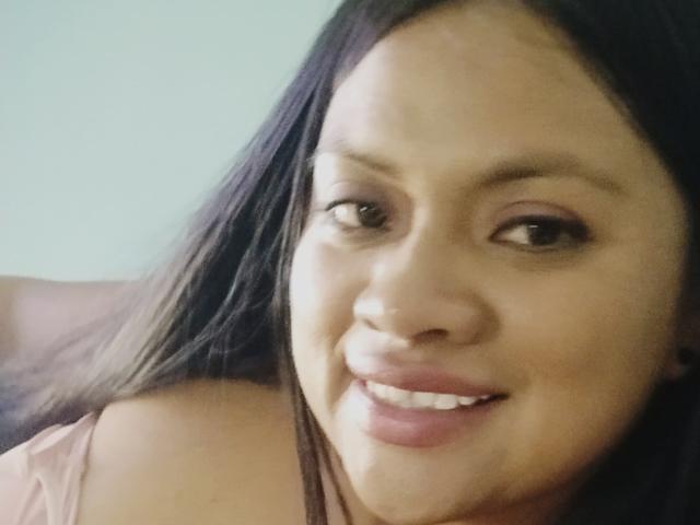 Dahiana Coleman tiene el cabello largo y negro, ojos marrones y un tono de piel claro. Está sonriendo, lleva lápiz labial rosa, y hay una pequeña cantidad de líquido blanco en su barbilla..