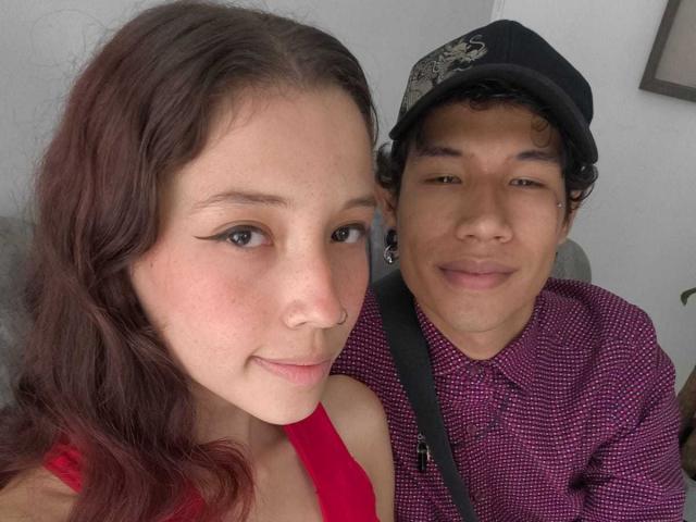 Roxan ha il rossetto rosso e i capelli castani ondulati, indossa una maglietta rossa, ed è accanto a Noah, che ha i capelli ricci, un berretto nero e una maglietta viola, ed è sorridente..