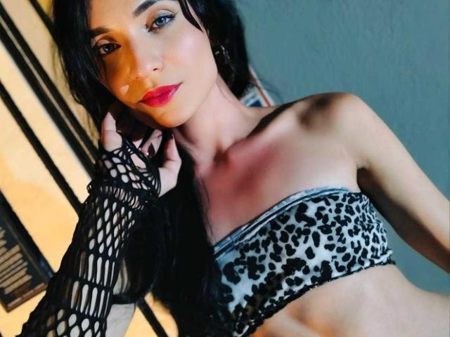PamelaKander with black fishnet glove, leopard print strapless top, red lipstick, and long black hair, smiling slightly, holding her hair. Her tits are small, she's sexy.