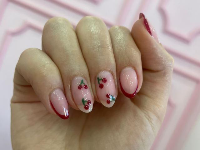 AlannaN's hand with pink-nail polish, red tips, and red cherry nail art on fingers, glossy, soft skin, gently curled fingers, pink background, pastel, delicate, cute.