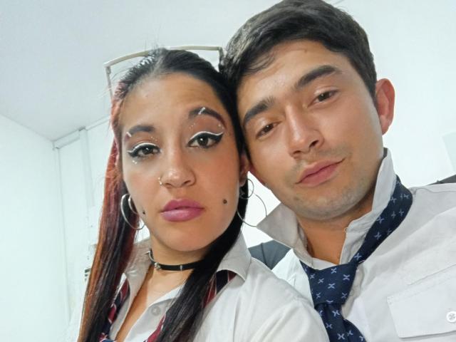 BonniClark with dark hair and pink lipstick, wearing a school uniform, nose piercing, and hoop earrings, stands next to a man in a white shirt and patterned tie.