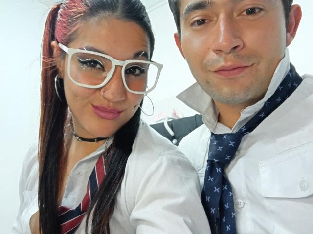 BonniClark with red ponytail, white glasses, nose ring, and choker, wearing a school uniform. Beside her is a guy in a white shirt and patterned tie.