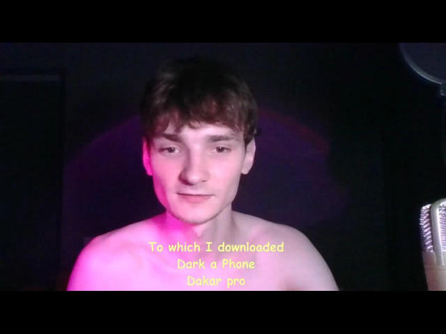 Shirtless DrashHot with short brown hair and a slight smile, pinkish light on face, text below, holding a phone. Text reads "To which I downloaded back a phone caller..."