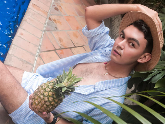 DeusBeauty with light brown skin, short dark hair, wearing a straw hat, blue striped shirt, holding a pineapple, sitting by a blue pool, looking at camera with a relaxed expression.