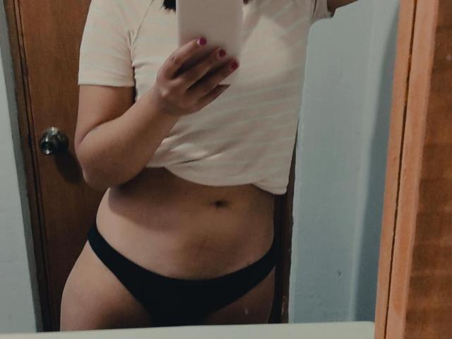 La foto de AmberxOne la muestra con una camiseta blanca a rayas levantada para mostrar su vientre plano, ropa interior negra y esmalte de uñas rosa, mientras se toma una foto frente al espejo..