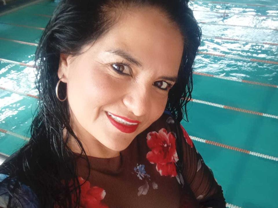 SailorOne has wet black hair, red lipstick, and floral sheer top, smiling with hoop earrings, showing small tits and a cute face, standing by a green-tiled pool.