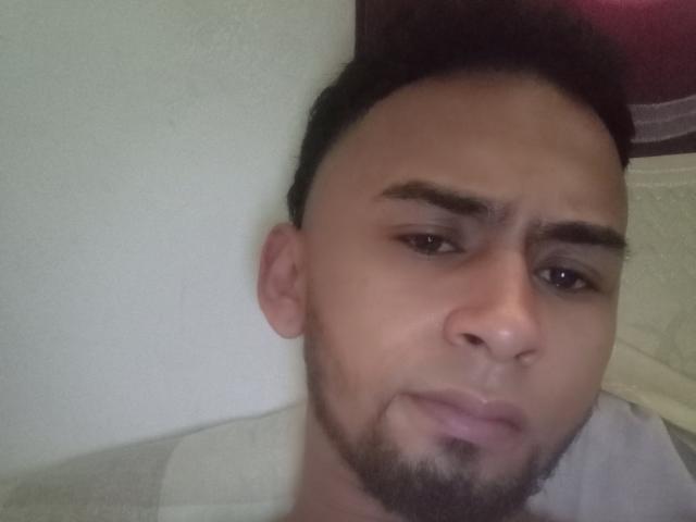 ElnegritoMedellin has a pensive, slightly annoyed face with dark eyebrows, short black hair, and a small beard. His skin is light brown, and he's looking to the side.
