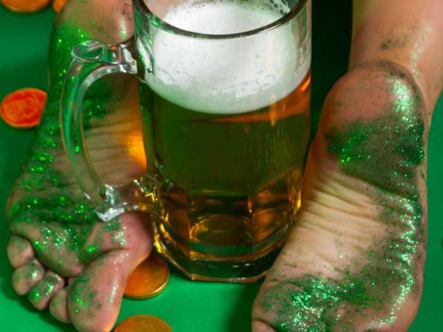 SamanthaJonnes' dirty feet, covered in green glitter, rest on a green surface with a glass of beer, foamy top, and a handle, surrounded by scattered coins.