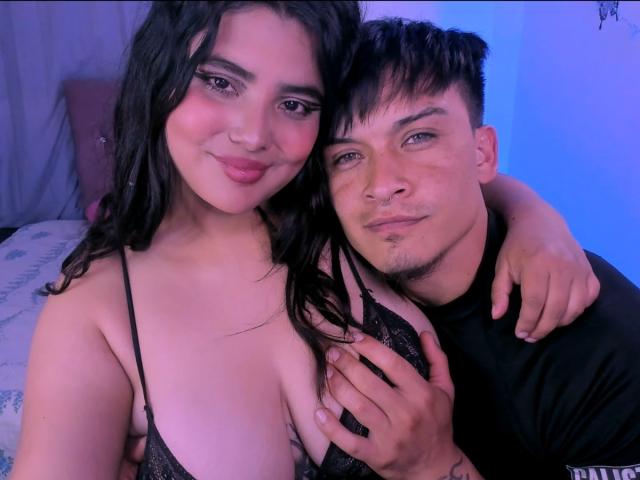 TommyAndGrace with long black hair and pouty lips, wearing a black lace bra, has her tits grabbed by TommyAndGrace with short black hair and a nose ring.
