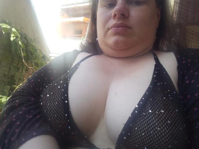 LeviSweetheart está desnudo, con las manos en la cabeza, vistiendo una máscara negra y un collar, mostrando una espalda tonificada y musculosa, y un pene flácido, sin circuncidar, ligeramente visible..