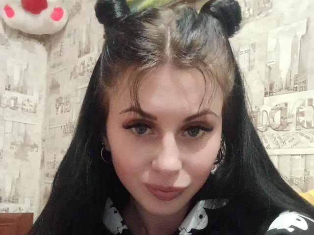 EvelynLaFire, con i capelli neri e le orecchie a forma di orso, indossa una maglietta nera e bianca, ha gli occhi azzurri, l'eyeliner nero e un sorriso leggero, con piccoli orecchini, in un selfie..