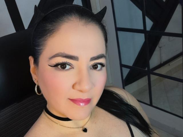 ValeryDark has dark hair, cat ears, and black eyeliner. She's wearing pink lipstick, a black choker, and gold hoop earrings. Her tits are slightly visible.