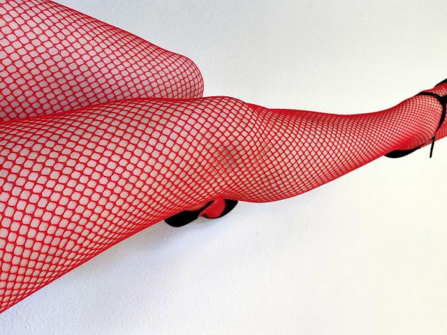 Claudias' legs in red fishnet stockings, showing a sexy, curvy, and attractive view, with black high heels, stretching out horizontally.