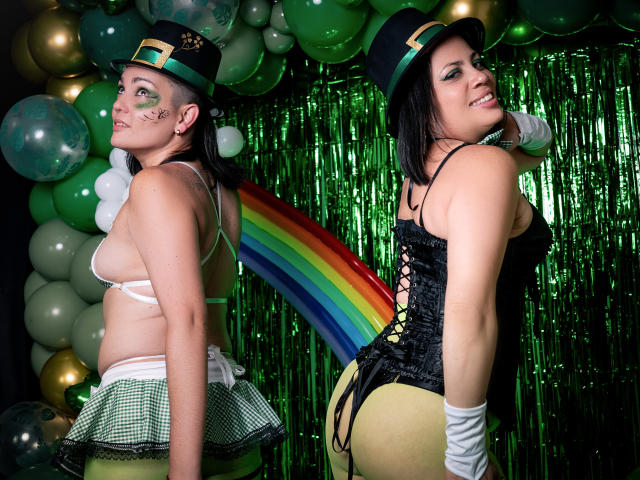 SaharaMK has green eyes, black hair, and wears a green and black hat with a gold buckle. She's topless with small tits, a green check skirt, and a black corset.